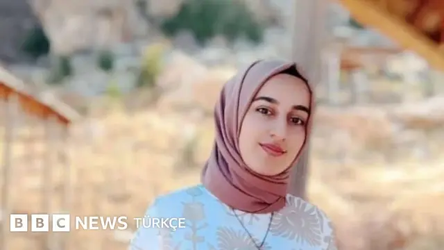Rojin Kabaiş'in tek başına gülümseyerek kadraja baktığı bir fotoğrafı. Üzerinde beyaz bir kıyafet ve somon rengi bir başörtüsü var